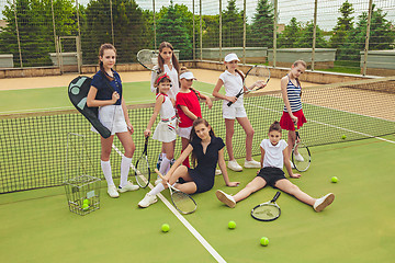 Image showing Portrait of group of girls as tennis players holding tennis racket against green grass of outdoor court