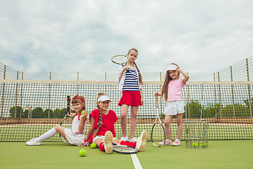 Image showing Portrait of group of girls as tennis players holding tennis racket against green grass of outdoor court