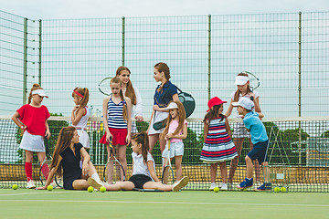 Image showing Portrait of group of girls as tennis players holding tennis racket against green grass of outdoor court