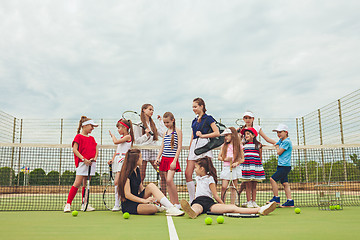 Image showing Portrait of group of girls as tennis players holding tennis racket against green grass of outdoor court