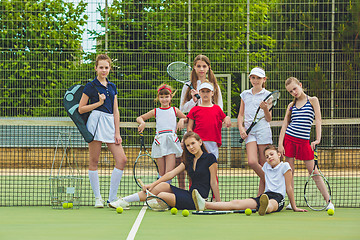 Image showing Portrait of group of girls as tennis players holding tennis racket against green grass of outdoor court