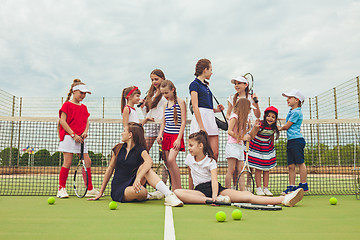 Image showing Portrait of group of girls as tennis players holding tennis racket against green grass of outdoor court