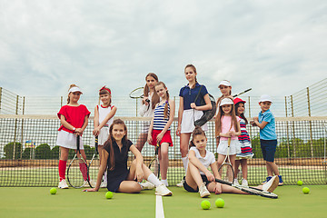 Image showing Portrait of group of girls as tennis players holding tennis racket against green grass of outdoor court