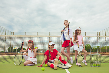 Image showing Portrait of group of girls as tennis players holding tennis racket against green grass of outdoor court