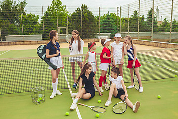 Image showing Portrait of group of girls as tennis players holding tennis racket against green grass of outdoor court