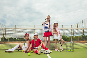 Image showing Portrait of group of girls as tennis players holding tennis racket against green grass of outdoor court