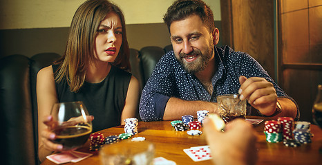 Image showing Friends sitting at wooden table. Friends having fun while playing board game.