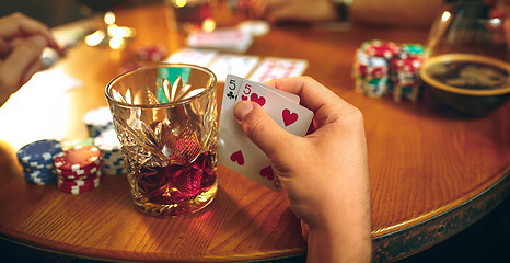 Image showing Side view photo of friends sitting at wooden table. Friends having fun while playing board game.