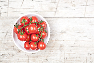 Image showing Fresh tomatoes in white bowl on rustic wooden table.