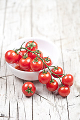 Image showing Fresh tomatoes in white bowl on rustic wooden table. 