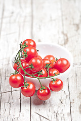 Image showing Fresh tomatoes in white bowl on rustic wooden table. 