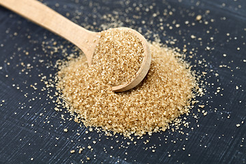 Image showing Brown cane sugar in wooden spoon on black board.