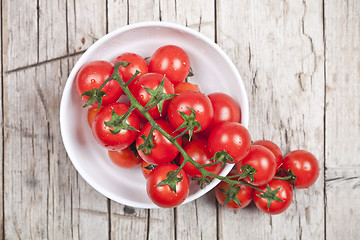 Image showing Fresh tomatoes in white bowl on rustic wooden table. 