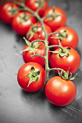 Image showing Fresh organic cherry tomatoes bunch closeup on black board.