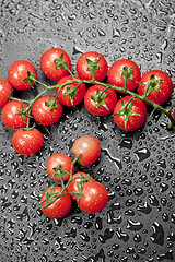 Image showing Fresh organic wet cherry tomatoes bunch closeup on black