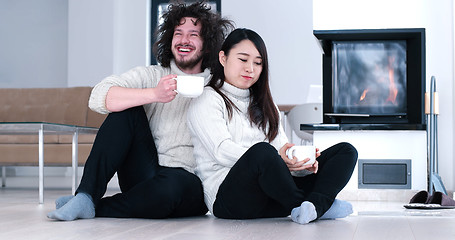 Image showing multiethnic romantic couple  in front of fireplace