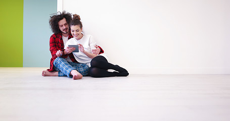 Image showing Young Couple using digital tablet on the floor