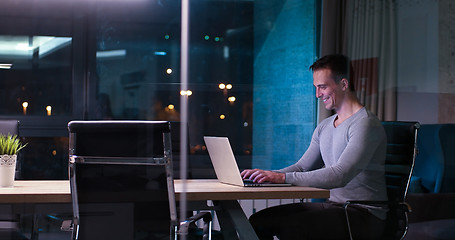 Image showing man working on laptop in dark office