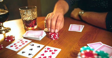 Image showing Side view photo of friends sitting at wooden table. Friends having fun while playing board game.