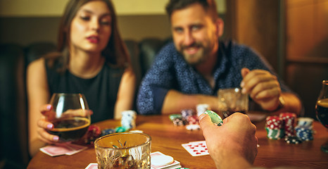 Image showing Friends sitting at wooden table. Friends having fun while playing board game.