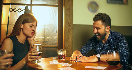 Image showing Friends sitting at wooden table. Friends having fun while playing board game.