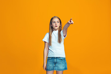 Image showing The happy teen girl pointing to you, half length closeup portrait on orange background.