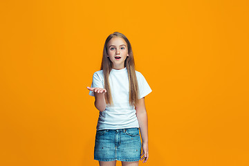 Image showing Beautiful female half-length portrait on orange studio backgroud. The young emotional teen girl