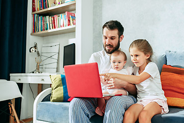 Image showing Proud father holding his baby daughters at home