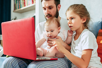 Image showing Proud father holding his baby daughters at home