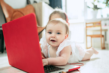 Image showing Portrait of little baby girl looking at camera with a laptop