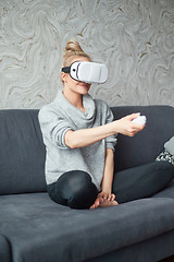 Image showing Young woman watching videos or playing with VR glasses on head