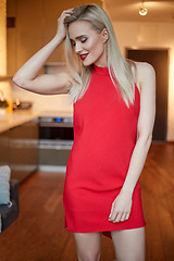 Image showing Stylish elegant blonde woman in home living room, wearing red sexy dress