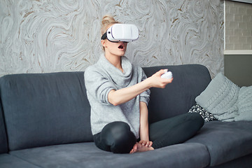 Image showing Young woman watching videos or playing with VR glasses on head