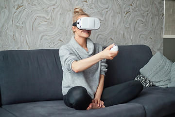 Image showing Young woman watching videos or playing with VR glasses on head