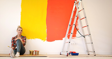 Image showing young female painter sitting on floor