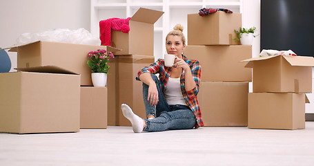 Image showing woman with many cardboard boxes sitting on floor