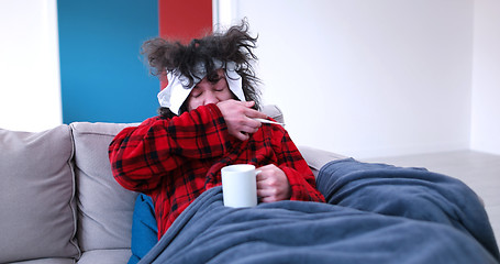 Image showing sick man is holding a cup while sitting on couch