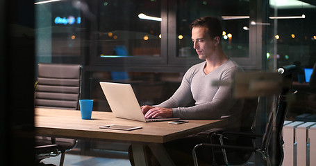 Image showing man working on laptop in dark office