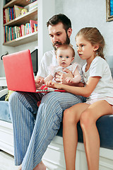 Image showing Proud father holding his baby daughters at home