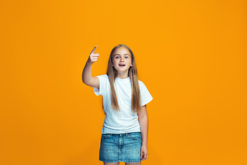 Image showing Beautiful female half-length portrait on orange studio backgroud. The young emotional teen girl