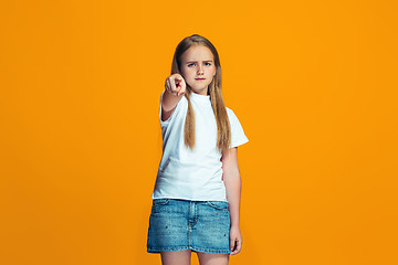 Image showing The happy teen girl pointing to you, half length closeup portrait on orange background.