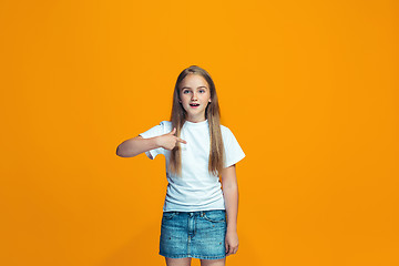 Image showing Beautiful female half-length portrait on orange studio backgroud. The young emotional teen girl
