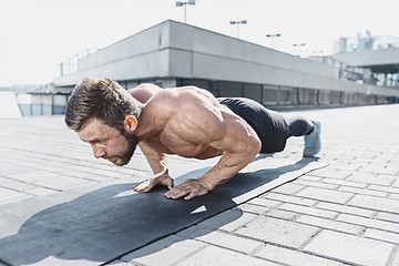 Image showing Fit fitness man doing fitness exercises outdoors at city