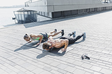 Image showing Fit fitness woman and man doing fitness exercises outdoors at city