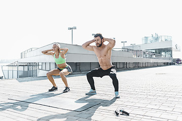 Image showing Fit fitness woman and man doing fitness exercises outdoors at city