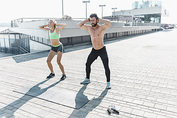Image showing Fit fitness woman and man doing fitness exercises outdoors at city