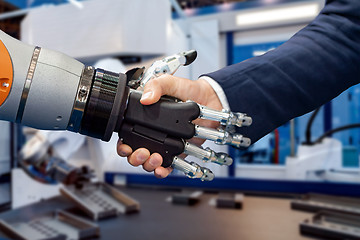 Image showing Hand of a businessman shaking hands with a Android robot.