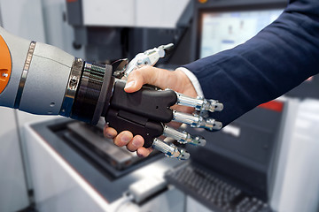 Image showing Hand of a businessman shaking hands with a Android robot.