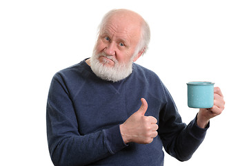 Image showing elderly man with cup of bad tea or coffee showing thumb up isolated on white