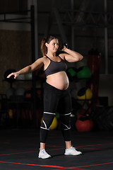 Image showing Pregnant female athlete doing hang kettlebell clean and press